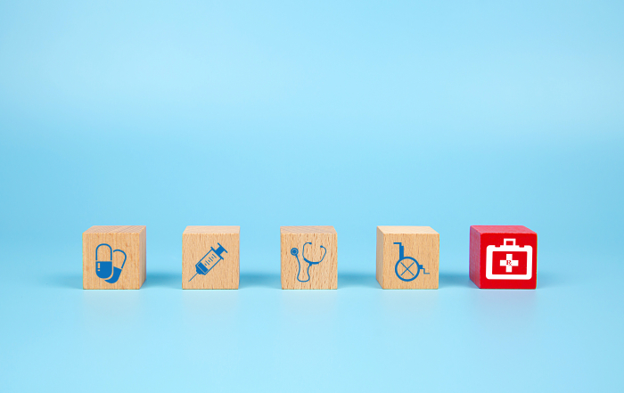 Cube wooden toy blocks with medical and first aid kid icon. Concepts of illness treatment and health insurance.